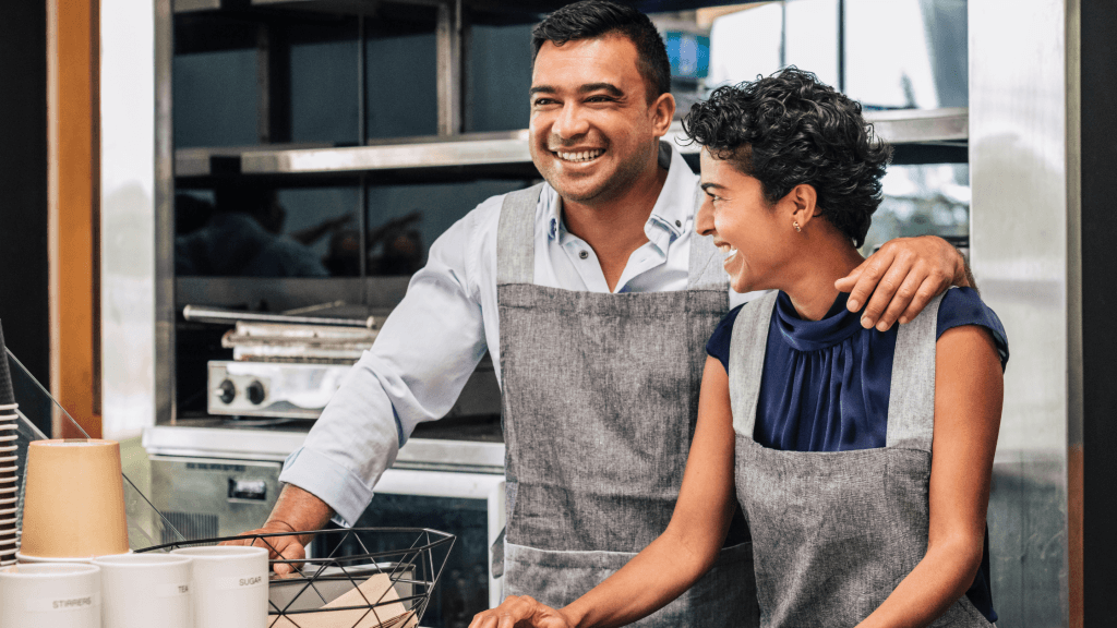 Two smiling business owners in aprons in their kitchen