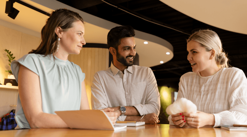 Three colleagues chatting around an office table