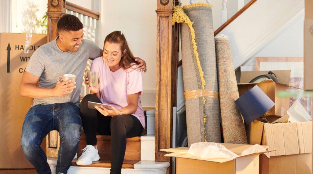 Couple taking a coffee break among moving boxes