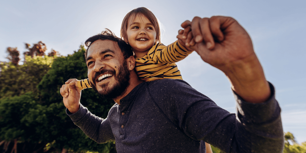 Father carrying his young daughter on his shoulders outdoors