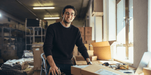 Smiling small business owner packing orders in his workshop