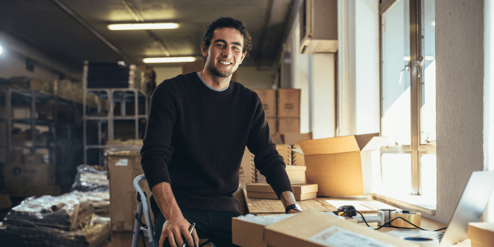 Smiling small business owner packing orders in his workshop